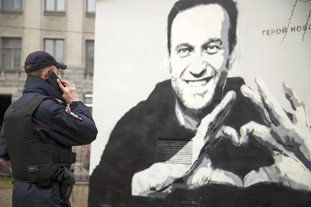 A police officer speaks on the phone near to graffiti of Russia's imprisoned opposition leader Alexei Navalny in St. Petersburg, Russia, Wednesday, April 28, 2021. (Photo by Ivan Petrov/AP Photo)