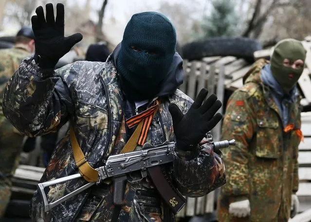 An armed man gestures in front of the police headquarters in Slaviansk, April 12, 2014. At least 20 armed militants wearing mismatched camouflage outfits took over the police and security services headquarters in the eastern city of Slaviansk seizing hundreds of handguns. (Photo by Gleb Garanich/Reuters)