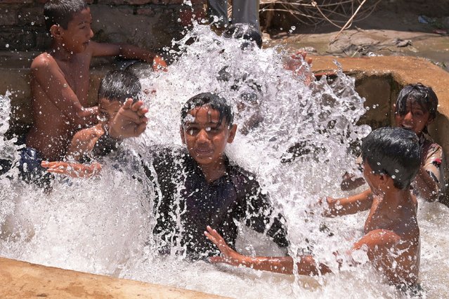 Boys play in the waters of a tubewell on a hot summer day in Hyderabad on May 6, 2024. Extensive scientific research has found climate change is causing heatwaves to become longer, more frequent and more intense. (Photo by Akram Shahid/AFP Photo)