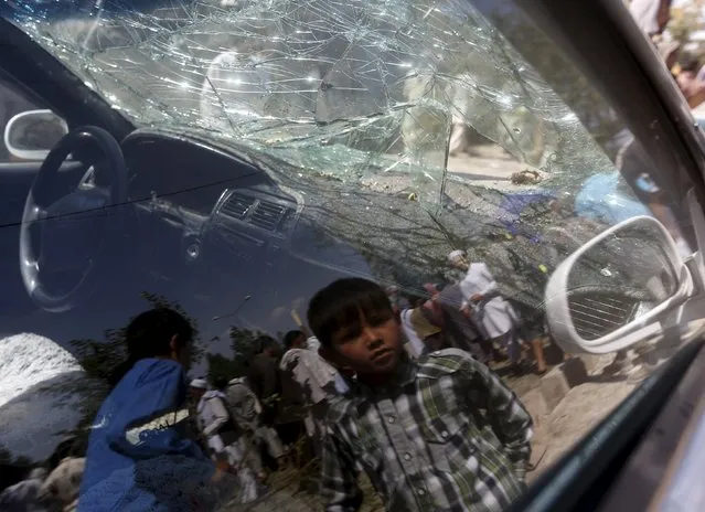 An Afghan boy is reflected on the window of a damaged vehicle at the site of a car bomb in Kabul, Afghanistan, June 30, 2015. (Photo by Omar Sobhani/Reuters)