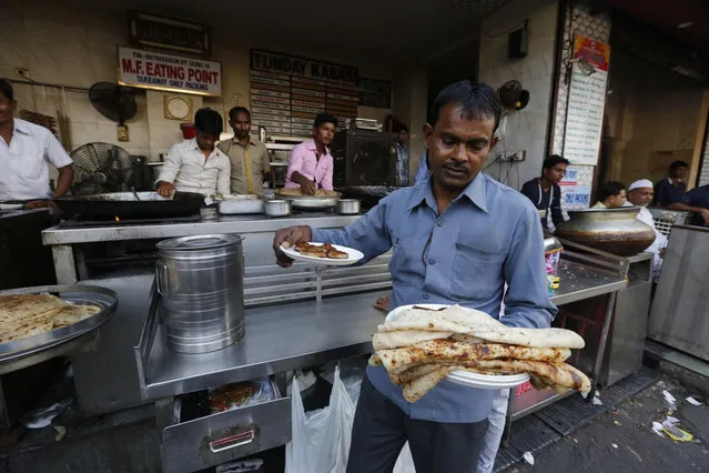 A waiter carries chicken kabab to serve at Tundey Kababi,  a 105-year-old kabab institution in Lucknow that has had to pull its top-selling spiced buffalo meat fare item from the menu because of the shortage of meat, in Lucknow, India , Friday, March 31, 2017. After the Hindu right-wing Bharatiya Janata Party came to power in Uttar Pradesh this month on the back of a resounding electoral victory and named a Hindu priest-cum-politician as the state's chief minister, the government began cracking down on illegal slaughterhouses and meat shops. “The majority of the slaughterhouses and meat shops are running without licenses and government approval. I know in the name of buffalo, cows are being slaughtered in many abattoirs. This should end”, the new chief minister Yogi Adityanath said. (Photo by Rajesh Kumar Singh/AP Photo)