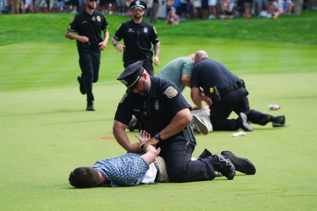 Police handcuff protesters on the eighteenth hole during the final round of the Travelers Championship golf tournament at TPC River Highlands in Cromwell, Connecticut on June 23, 2024. (Photo by /Reuters). (Photo by Gregory Fisher/USA TODAY Sports)