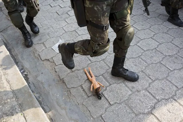 In this February 22, 2017 photo, a U.N. peacekeeper from Brazil sidesteps an abandoned doll left on a street of the Cite Soleil slum in Port-au-Prince, Haiti. The peacekeepers have earned praise for boosting security, paving the way to elections and providing crucial support after disasters. But some troops have also been accused of excessive force, rape and abandoning babies they fathered. (Photo by Dieu Nalio Chery/AP Photo)