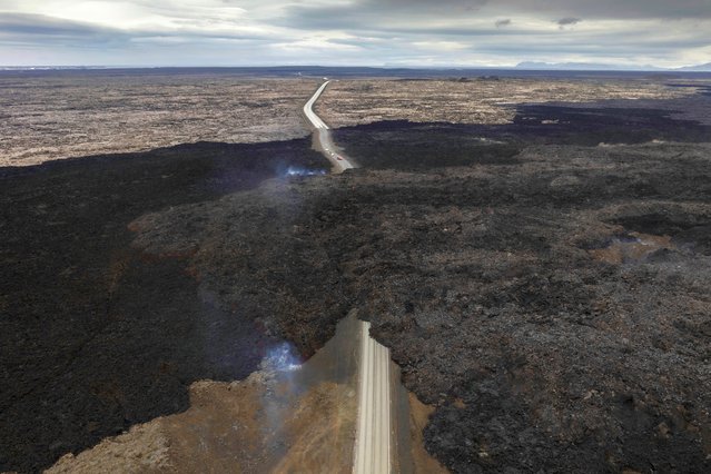 An aerial view shows lava from an active volcano engulfing the road near Grindavik, Iceland, Saturday, June 8, 2024. (Photo by Marco di Marco/AP Photo)