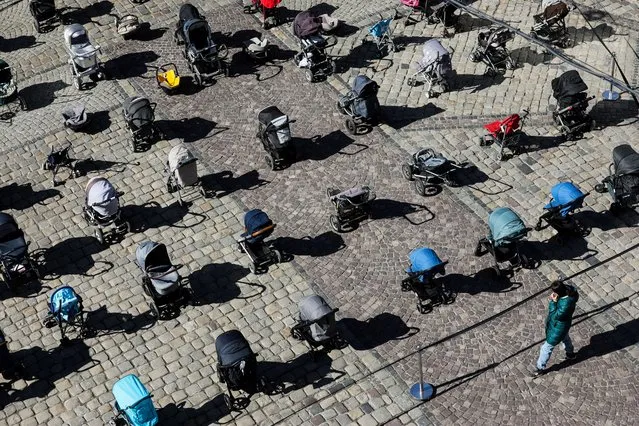 A person looks at 109 empty prams placed in the center of Lviv during the “Price of War” campaign organized by local activists and authorities to highlight the large number of children killed in ongoing Russia's invasion of Ukraine, in Lviv, March 18, 2022. (Photo by Roman Baluk/Reuters)