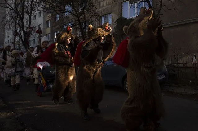 People from northern Romania perform the bear dance Christmas and New Year's ritual in Bucharest, Romania, Saturday, December 25, 2021. The bear dance tradition, originating in pre-Christian times, when dancers, wearing colored costumes or animal furs, went from house to house in villages singing and dancing to ward off evil, has moved to Romania's cities, where the ritual is performed for money. (Photo by Alexandru Dobre/AP Photo)