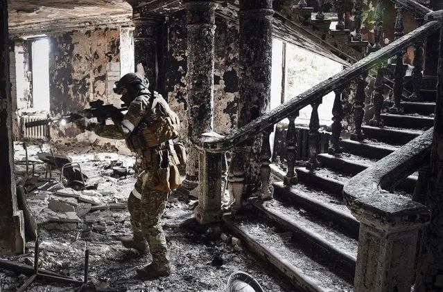 A Russian soldier patrols at the Mariupol drama theatre, bombed last March 16, on April 12, 2022 in Mariupol, as Russian troops intensify a campaign to take the strategic port city, part of an anticipated massive onslaught across eastern Ukraine, while Russia's President makes a defiant case for the war on Russia's neighbour. (Photo by Alexander Nemenov/AFP Photo)