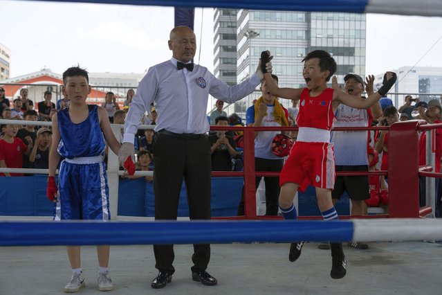 Twelve-year-old Gerelt-Od Kherlen, in red, reacts after winning a bronze medal boxing match on Sukhbaatar Square in Ulaanbaatar, Mongolia, Tuesday, July 2, 2024. Growing up in a ger district without proper running water, Gerelt-Od fetched water from a nearby kiosk every day for his family. Carrying water and playing ball with his siblings and other children made him strong and resilient. (Photo by Ng Han Guan/AP Photo)