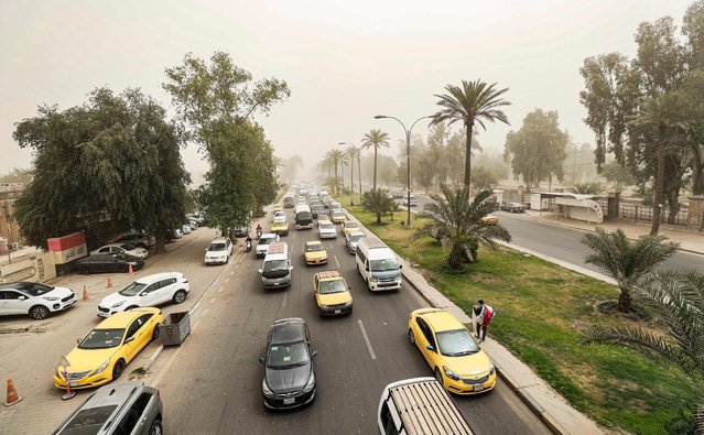Vehicles drive along a road during a severe dust storm in Iraq's capital Baghdad on April 20, 2022. (Photo by Ahmad Al-Rubaye/AFP Photo)