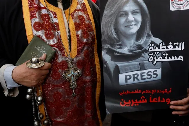 A priest holds a poster depicting Al Jazeera reporter Shireen Abu Akleh who was killed in an Israeli raid, in Ramallah, in the Israeli-occupied West Bank on May 11, 2022. (Photo by Mohamad Torokman/Reuters)