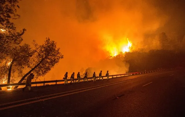 Cal Fire firefighters walk along Highway 20 as the Rocky fire burns near Clear Lake, California on August 2, 2015. The fire has charred more than 27,000 acres, and is currently only 5% contained. (Photo by Josh Edelson/AFP Photo)