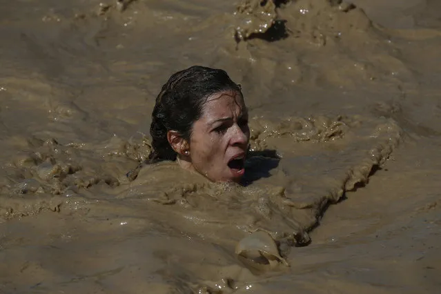 A participant swims in the mud pool during the Mud Day athletic event at El Goloso Military base on the outskirts of Madrid, Spain, Saturday, June 11, 2016. (Photo by Paul White/AP Photo)