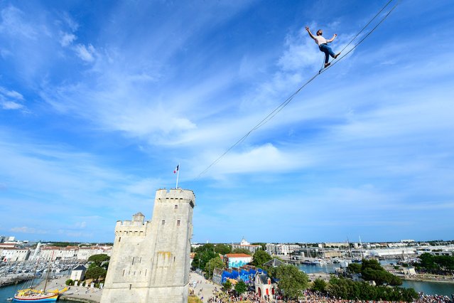 Tightrope walker Nathan Paulin performs a 50-meter-high and 277-meter-long rope displayed between the Lantern Tower and the Saint-Nicolas Tower above the old port in La Rochelle, France on June 7, 2023. (Photo by Mehdi Fedouach/AFP Photo)