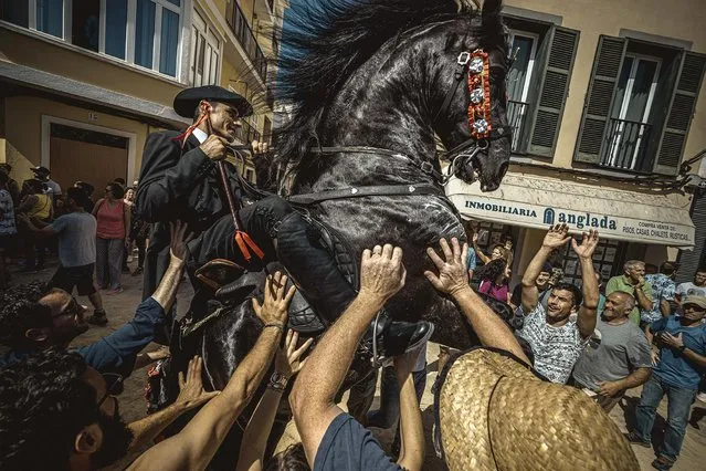 A “caixer” (horse rider) rears up on his horse surrounded by a cheering crowd prior to the “Caragol des Born” parade on the eve of the traditional “Sant Joan” (Saint John) festival in Ciutadella de Menorca, Balearic Islands, Spain on June 23, 2019. (Photo by Matthias Oesterle/EPA/EFE/Rex Features/Shutterstock)