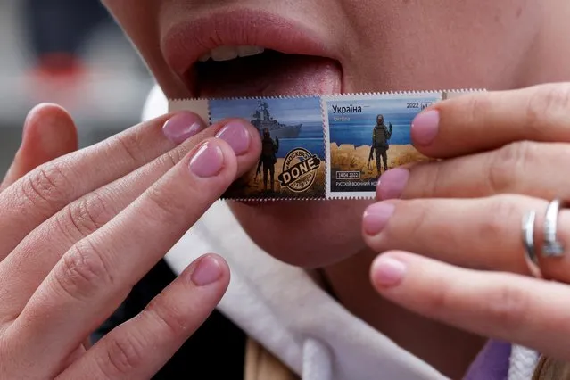 A woman licks a new series of commemorative Snake Island anti-Russian stamps as she speaks to the media, amid the Russian invasion of Ukraine, outside the post office in Kyiv, Ukraine, May 23, 2022. (Photo by Edgar Su/Reuters)