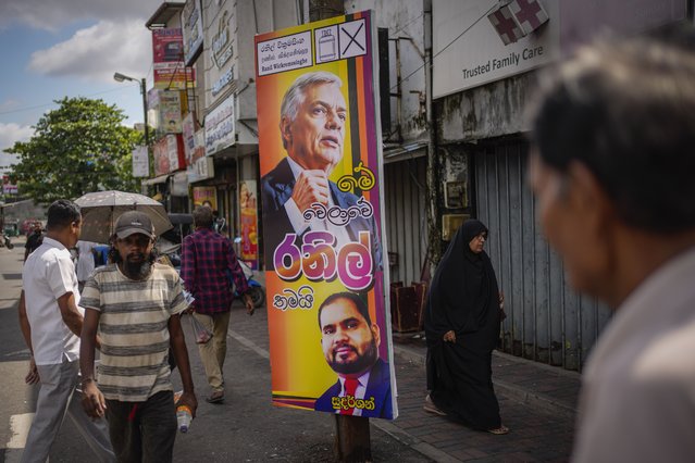 People walk past election propaganda of President Ranil Wickremesinghe, top, in Colombo, Sri Lanka, Monday, September 16, 2024. (Phoot by Eranga Jayawardena/AP Photo)