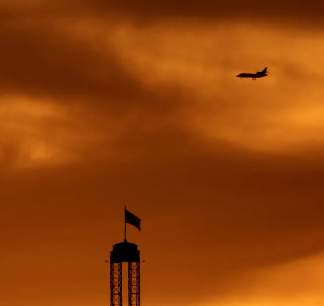 A plane is silhouetted as the sun sets beyond Worlds of Fun amusement park, Thursday, July 30, 2015, in Kansas City, Mo. (Photo by Charlie Riedel/AP Photo)