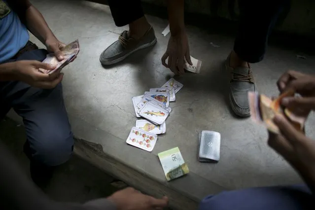 In this May 31, 2016 photo, boys gamble on a card game in the patio of their public high school in Caracas, Venezuela. As many as 40 percent of teachers skip class on any given day to wait in food lines, according to the Venezuela Teacher's Federation. The school director has asked nearby supermarkets to let teachers cut in line, and she's disciplined staff for selling students passing grades in exchange for scarce goods like milk and flour. (Photo by Ariana Cubillos/AP Photo)