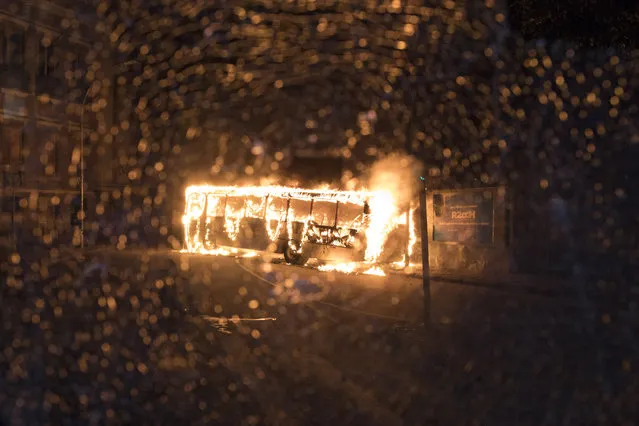 In this Friday, April 28, 2017 photo, seen through a shattered bus window, another bus burns after it was set fire by protesters during a general strike in Rio de Janeiro, Brazil. Public transport largely came to a halt across much of Brazil on Friday and protesters blocked roads and scuffled with police as part of a general strike to protest proposed changes to labor laws and the pension system. (Photo by Leo Correa/AP Photo)