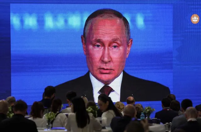 Participants gather near a screen showing Russian President Vladimir Putin, who delivers a speech at the St. Petersburg International Economic Forum (SPIEF) in Saint Petersburg, Russia on June 17, 2022. (Photo by Anton Vaganov/Reuters)