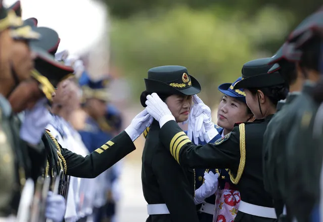 A female member of the honor guard reacts as another one helps to adjust her cap ahead of an official welcoming outside the Great Hall of the People in Beijing. (Photo by Jason Lee/Reuters)