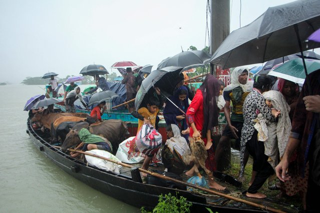 People prepare to get of a boat after being evacuated from a flooded area following heavy monsoon rainfalls on the outskirts of Sylhet on June 17, 2022. Bangladesh has deployed troops to help two million people stranded by floods after relentless monsoon rains inundated huge swathes of territory for the second time in weeks, officials said on June 17. (Photo by AFP Photo/Stringer)