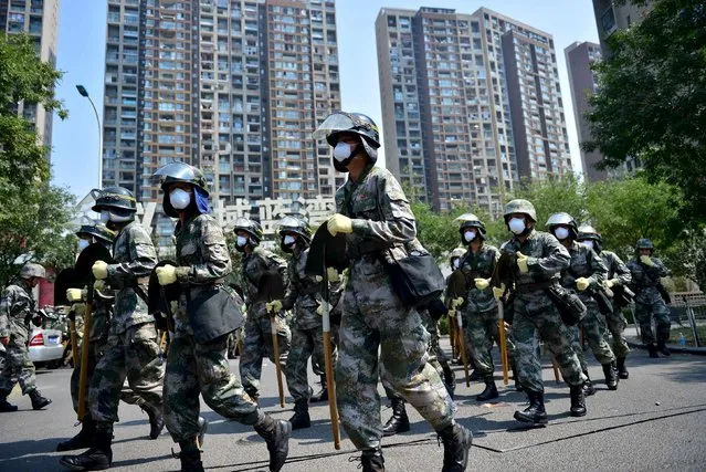 Paramilitary policemen with shovels run in front of a damaged residential area, near the site of the explosions at the Binhai new district, Tianjin, China, August 16, 2015. Two explosions in the Chinese port city of Tianjin that killed more than 100 people last week could generate total insurance losses of between $1 billion and $1.5 billion, Credit Suisse analysts said citing initial estimates from Chinese media. (Photo by Reuters/China Daily)