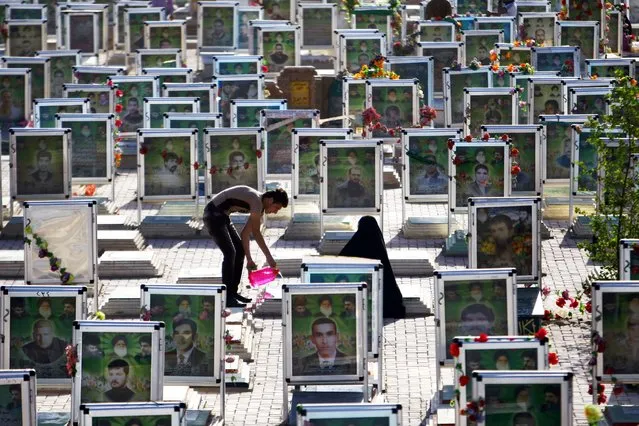 Iraqi Shiites clean the grave of a relative at one of the world's biggest cemeteries in the holy city of Najaf, on July 29, 2014, during the Eid al-Fitr celebrations marking the end of the Muslim fasting month of Ramadan. (Photo by Haidar Hamdani/AFP Photo)