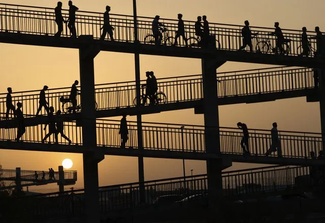 People cross an overhead bridge amid soaring humidity and temperatures in the Gulf emirate of Dubai, on June 24, 2022. (Photo by Karim Sahib/AFP Photo)