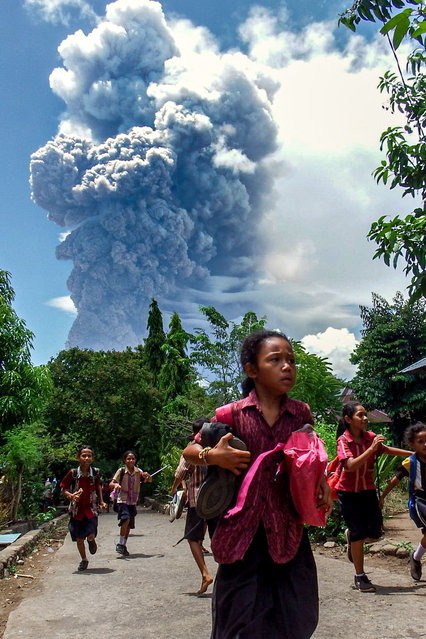 Schoolchildren run during the eruption of Mount Lewotobi Laki-Laki, as seen from Lewolaga village in East Flores, East Nusa Tenggara on November 7, 2024. (Photo by Arnold Welianto/AFP Photo)