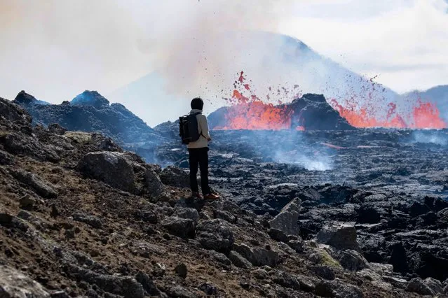 A person looks on the scene of the newly erupted volcano taking place in Meradalir valley, near mount Fagradalsfjall, Iceland on August 4, 2022. The eruption is some 40 kilometres (25 miles) from Reykjavik, near the site of the Mount Fagradalsfjall volcano that erupted for six months in March-September 2021, mesmerising tourists and spectators who flocked to the scene. (Photo by Jeremie Richard/AFP Photo)