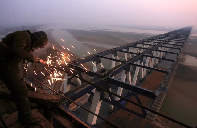 A worker welds steel frames at a construction site of a railway bridge in Zhengzhou, Henan province December 17, 2009. (Photo by Donald Chan/Reuters)