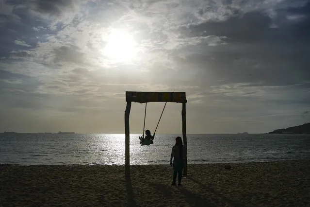 A child on a swing is silhouetted on the waters of Manza beach, during a sunset in Lecheria, Venezuela, Friday, July 1, 2022. (Photo by Matias Delacroix/AP Photo)