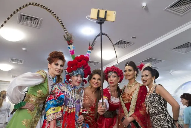 Participants take a photo with a smartphone on a selfie stick as they wait backstage before the “Mrs Universe 2015” contest in Minsk, Belarus, August 29, 2015. (Photo by Vasily Fedosenko/Reuters)