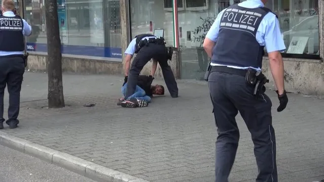 In this grab taken from video, police arrest a man in Reutilingen, Germany, Sunday, July 24, 2016. A Syrian man killed a woman with a machete and wounded two others Sunday outside a bus station in the southwestern German city of Reutlingen before being arrested. Police said there were no indications pointing to terrorism. (Photo by Nonstop News via AP Photo)