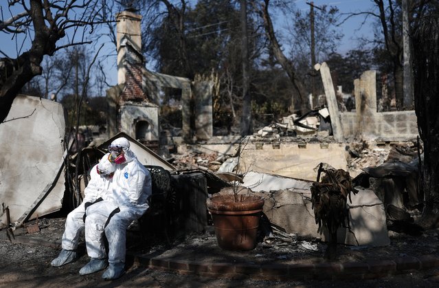 A couple wearing full protective gear rest while searching through the remains of their home which burned in the Eaton Fire on January 19, 2025 in Altadena, California. They said they plan to rebuild. Multiple wildfires which were fueled by intense Santa Ana Winds have burned across Los Angeles County leaving at least 27 dead with over 180,000 people having been under evacuation orders. Over 12,000 structures, many of them homes and businesses, burned in the Palisades and Eaton Fires. (Photo by Mario Tama/Getty Images)
