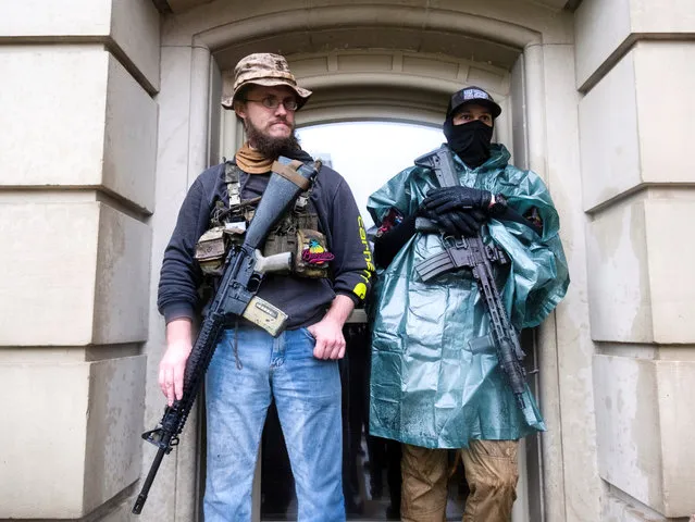 Protesters with long guns shelter from the heavy rain during a protest against Governor Gretchen Whitmer's extended stay-at-home orders intended to slow the spread of the coronavirus disease (COVID-19) at the Capitol building in Lansing, Michigan, U.S. May 14, 2020. (Photo by Seth Herald/Reuters)