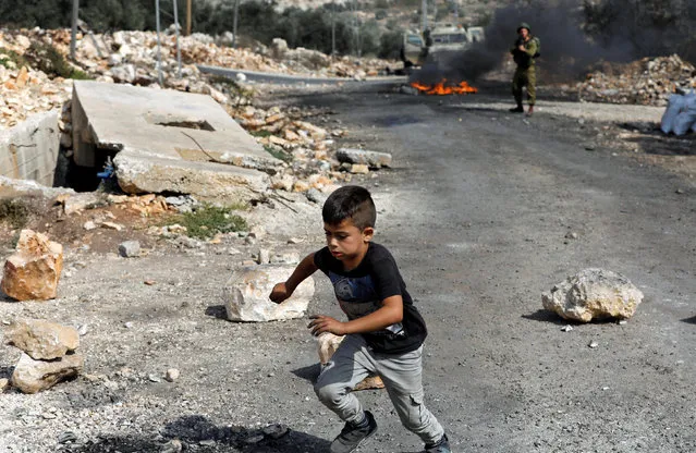A Palestinian boy runs for cover during clashes with Israeli troops near the Jewish settlement of Qadomem, in the West Bank village of Kofr Qadom, near Nablus, October 20, 2017. (Photo by Mohamad Torokman/Reuters)