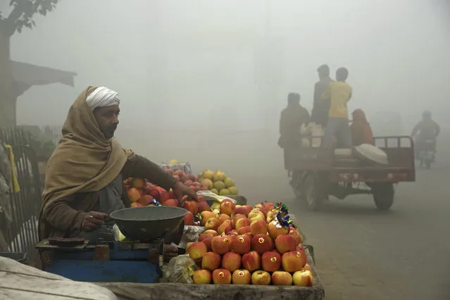 A vendor sells fruits on a foggy day in Lahore, Pakistan, Friday, November 10, 2017. Smog has enveloped much of Pakistan, causing highway accidents and respiratory problems, and forcing many residents to stay home, officials said. (Photo by K.M. Chaudary/AP Photo)