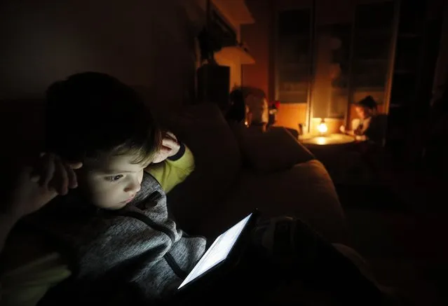 A little boy plays with a tablet during a planned power shutdown in Kyiv, Ukraine, 20 October 2022, amid the Russian invasion. About 40 percent of the total infrastructure of Ukraine was seriously damaged as a result of the Russian attacks, the Advisor to the Minister for Energy Affairs Oleksander Kharchenko announced during the national telethon. The repair work continues but we should expect that we will have not only emergency shutdowns but also planned shutdowns in order to reduce the load on the power grid, Kharchenko said. Russian troops entered Ukraine on 24 February 2022 starting a conflict that has provoked destruction and a humanitarian crisis. (Photo by Sergey Dolzhenko/EPA/EFE)