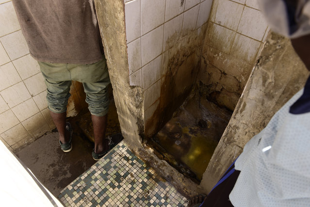 A picture taken on November 15, 2017 shows a man using a public toilet of Dakar, Senegal. (Photo by Seyllou/AFP Photo)