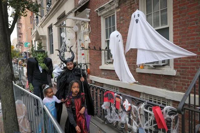 People in costumes walk past decorations in the West Village on Halloween in Manhattan, New York City, U.S., October 31, 2022. (Photo by Andrew Kelly/Reuters)