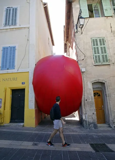 A passer-by walks past a huge red ball which is installed between two buildings as part of the RedBall Project by artist Kurt Perschke in Marseille, France, September 23, 2015. The RedBall Project is touring Marseille from September 19  to 25, 2015, changing its location each day. (Photo by Jean-Paul Pelissier/Reuters)