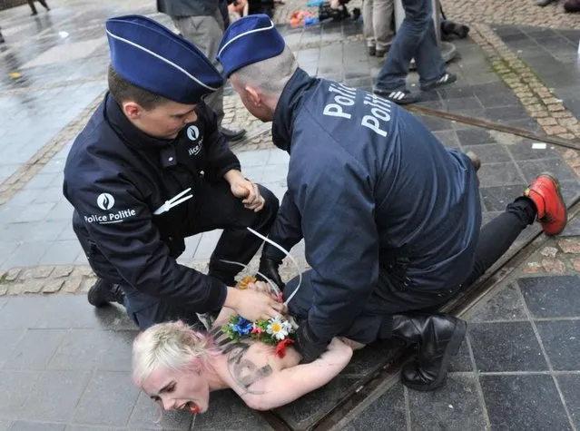 An activist of Ukraine's feminist movement Femen is taken away by the police as she demonstrates by the EU Council building where the EU-Russia summit is taking on December 21, 2012 in Brussels, Belgium. (Photo by Georges Gobet/AFP Photo)