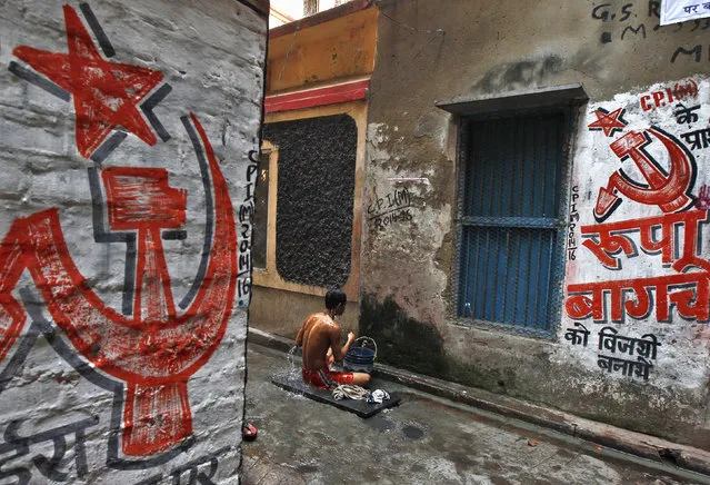 A man bathes in an alley with walls painted with the party symbol of Communist Party of India-Marxist (CPI-M) in Kolkata April 11, 2014. (Photo by Rupak De Chowdhuri/Reuters)
