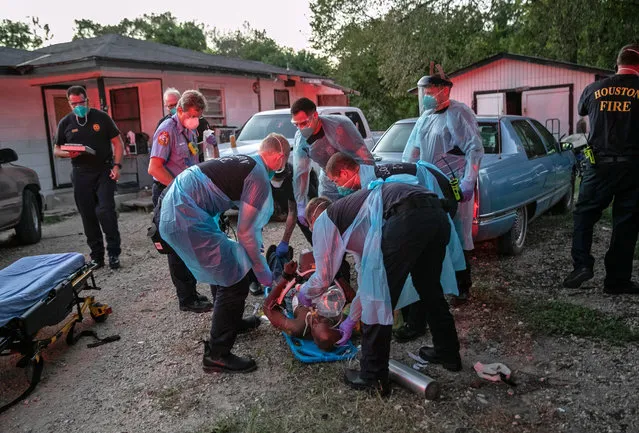 Houston Fire Department EMS medics prepare to transport a man to a hospital after he suffered cardiac arrest on August 11, 2020 in Houston, Texas. Heart failure is a frequent result of COVID-19. Firefighters and medics wear protective masks on all medical calls, whether patients have been tested for COVID-19 or not, in order to protect themselves from infection. (Photo by John Moore/Getty Images)