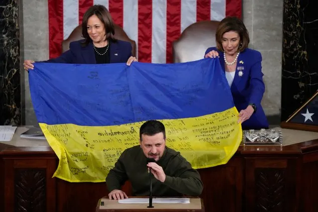 Vice President Kamala Harris and House Speaker Nancy Pelosi of Calif., right, react as Ukrainian President Volodymyr Zelenskyy presents lawmakers with a Ukrainian flag autographed by front-line troops in Bakhmut, in Ukraine's contested Donetsk province, as he addresses a joint meeting of Congress on Capitol Hill in Washington, Wednesday, December 21, 2022. (Photo by Jacquelyn Martin/AP Photo)