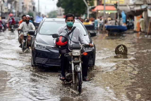 A motorcyclist (C) wearing a facemask as a preventive measure against the COVID-19 coronavirus makes his way on a street in the Pakistan's port city of Karachi on August 6, 2020. Pakistan on August 6 announced it would be lifting most of the country's remaining coronavirus restrictions after seeing new cases drop for several weeks. (Photo by Asif Hassan/AFP Photo)