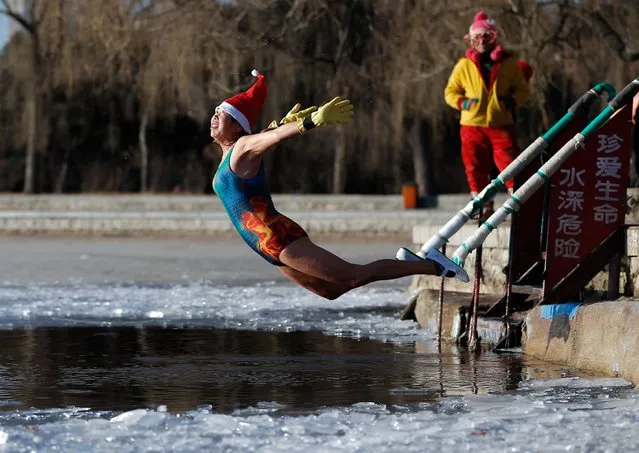 A woman wearing a Santa hat dives into a partly frozen lake in Shenyang in China's northeastern Liaoning province on December 25, 2017. (Photo by AFP Photo/Stringer)