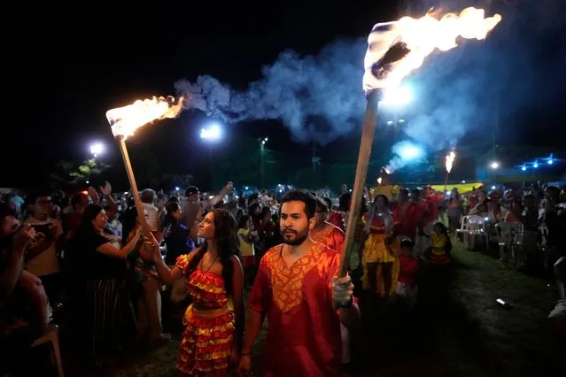 Members of the Paraguay-African cultural group Kamba Cua hold torches during celebrations in honor of Saint Balthazar, one of the Three Kings, on Epiphany in Fernando de la Mora, Paraguay, early Sunday, January 8, 2023. The annual procession is a tradition that keeps Paraguay's Afro-descendants connected with their African roots through ancestral dance, drumming and customs. (Photo by Jorge Saenz/AP Photo)